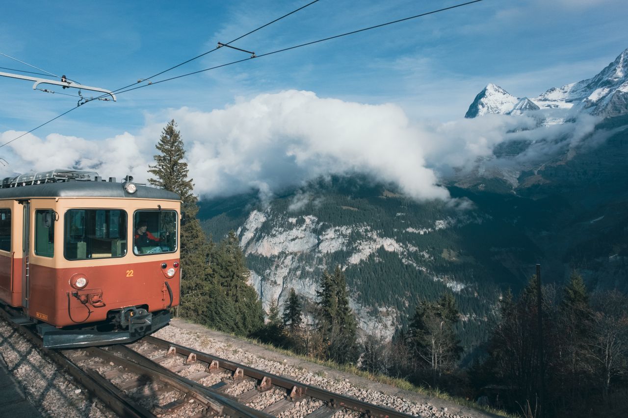 A picturesque train journey through the Swiss Alps with snowcapped mountains and lush forests.