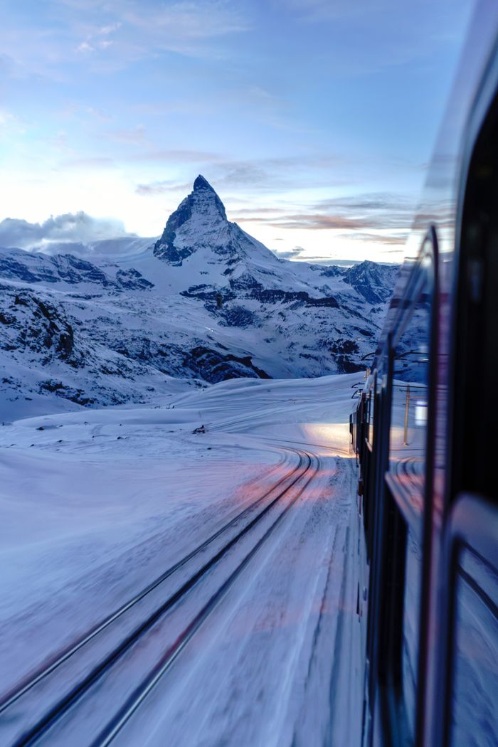 A picturesque train journey through the snow-covered Swiss Alps with the Matterhorn in view.