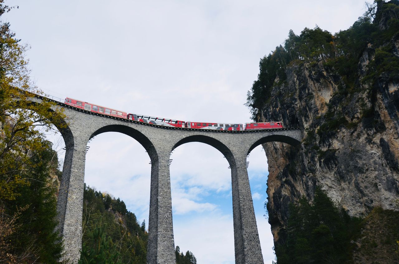 Stunning view of red train crossing the iconic Landwasser Viaduct in the Swiss Alps.