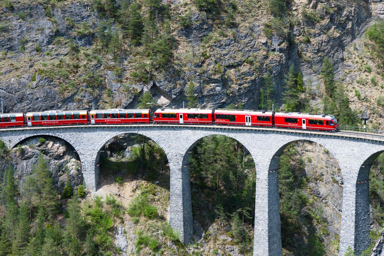 Stunning view of a red train crossing the iconic Landwasser Viaduct in the Swiss Alps.